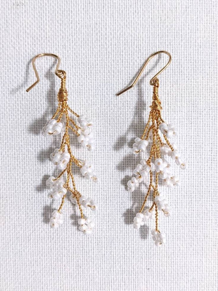 Bridal gold plated earrings features tiny white pearl seed beads in an elegant leaf branch design. The ear hooks are gold filled. Perfect style for any occasion!  Matching Items: HAIR ACCESSORIES: https://www.etsy.com/uk/listing/908001921/boho-bridal-gold-tiara-wedding-leaf  See my other BRIDAL EARRINGS: https://www.etsy.com/shop/MartalilyJewellery?section_id=40157901&order=date_desc&utm_source=boe&utm_medium=android&utm_campaign=9s_VaK7OSOqDwWwoOxvJNQ&utm_content=EARRINGS Please note that earri Statement Bridal Earrings, Earrings Seed Beads, Vine Earrings, Boho Wedding Earrings, Bridal Statement Earrings, Branch Earrings, Gold Tiara, Branch Design, Wedding Leaves