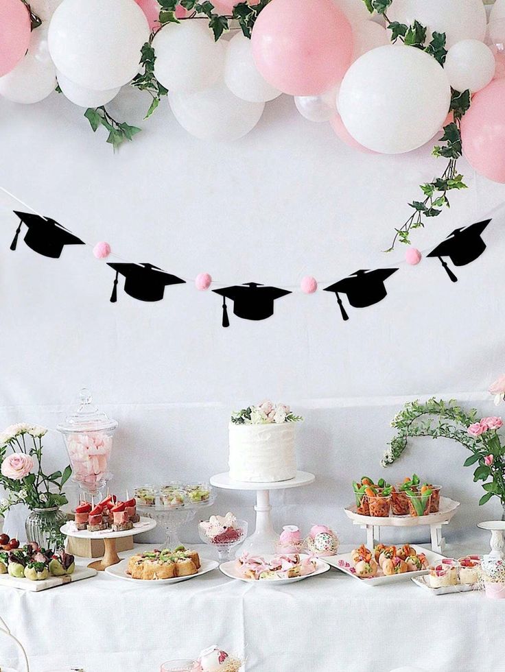 a table topped with cakes and desserts covered in pink and white frosted balloons