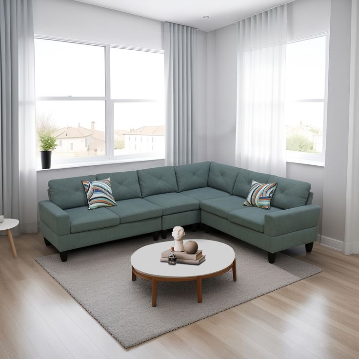 a living room with a sectional couch and coffee table in front of two windows that look out onto the ocean