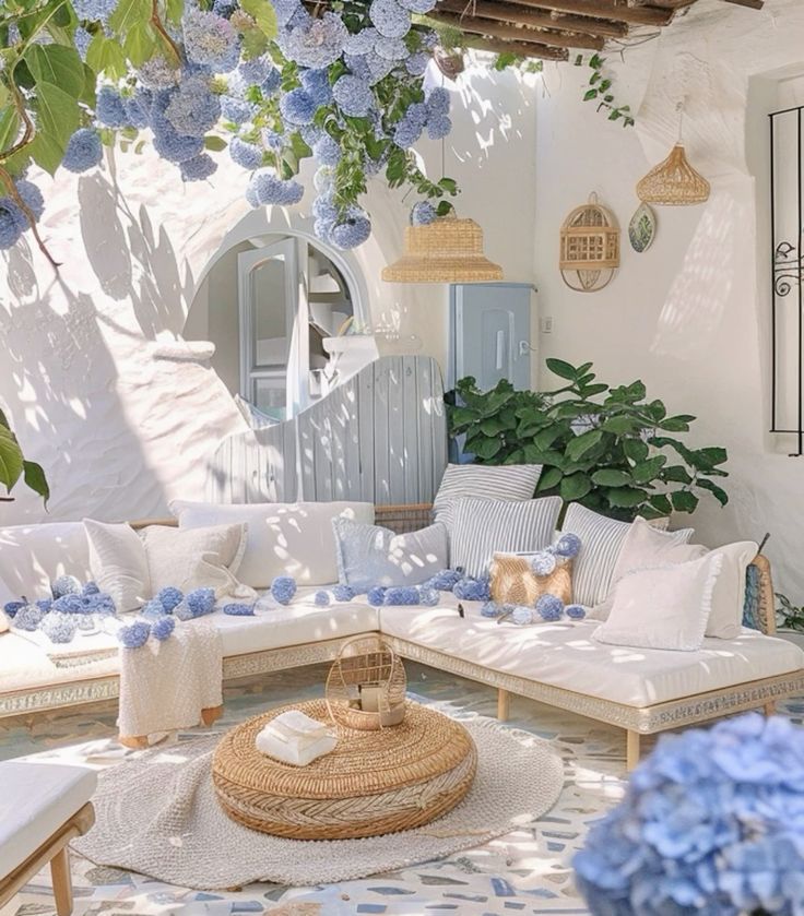 an outdoor living room with blue hydrangeas and wicker furniture on the floor