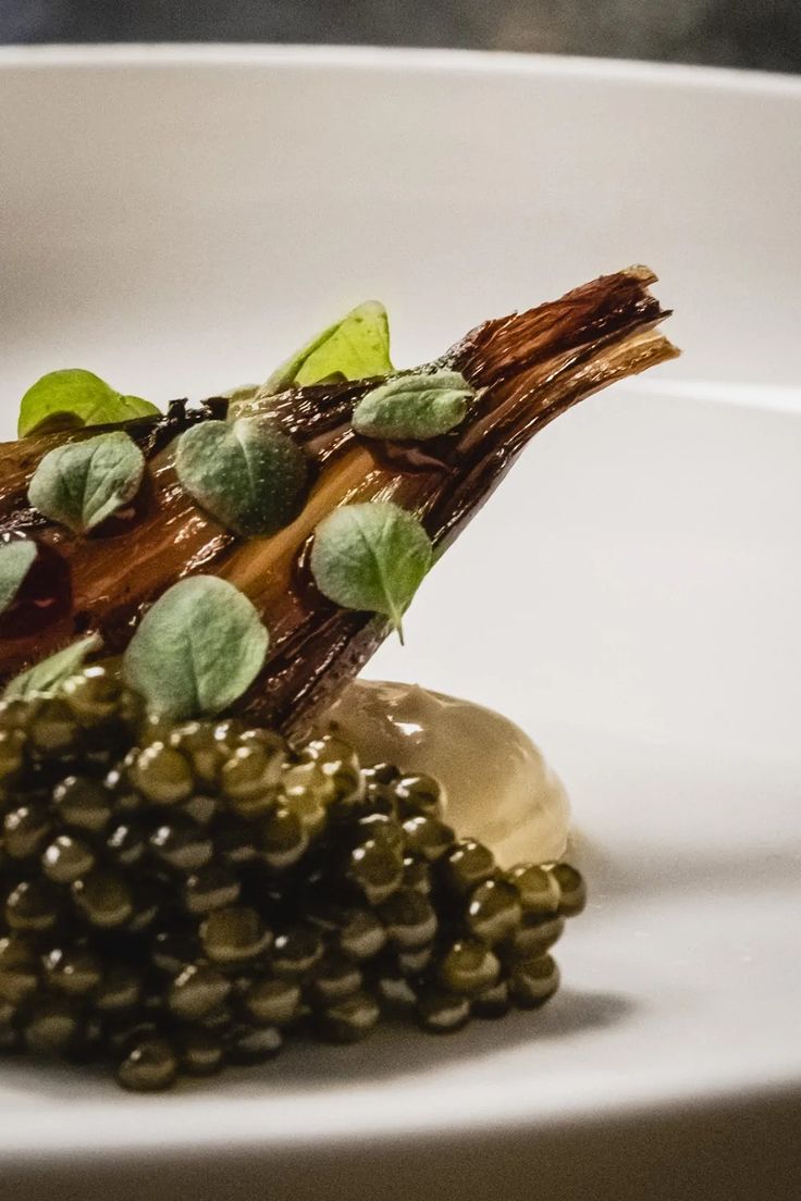 a white plate topped with green vegetables and sauce