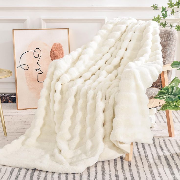 a large white blanket sitting on top of a rug next to a chair and potted plant