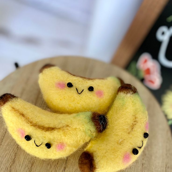 two yellow bananas with faces on them sitting on a wooden table next to a book