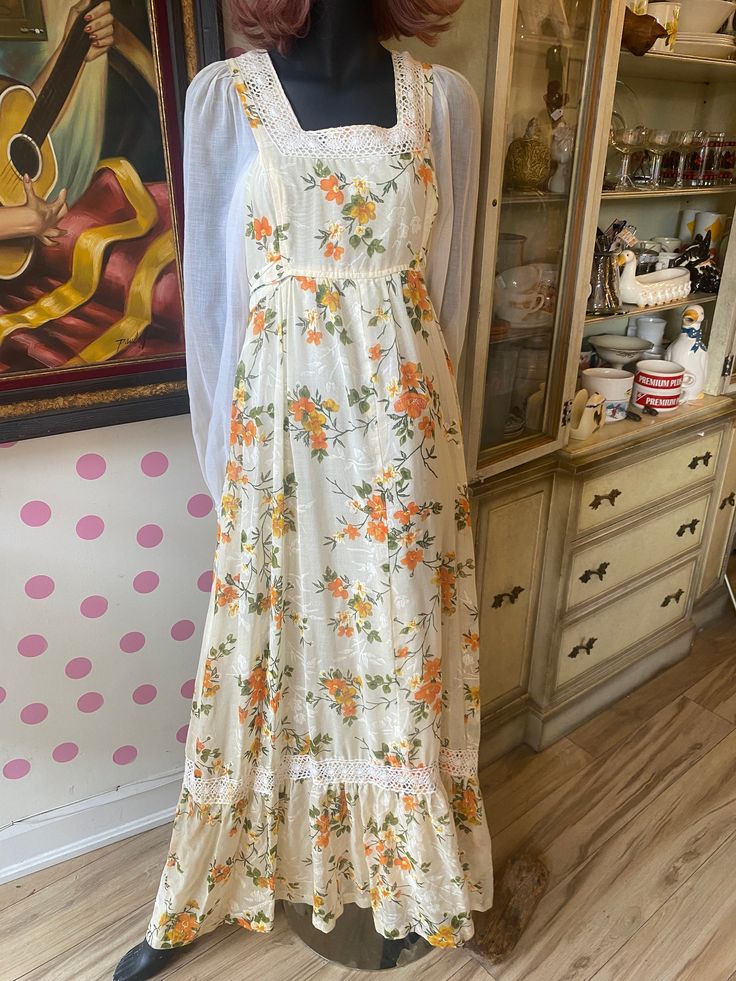 What a beauty!! This 1970's Prairie style dress is perfect for the summer and fall. This dress has a real Gunne Sax vibe however there is no label to say it is one.  The entire dress is in a cream colour with gold and and orange flowers with deep green stems and leaves. Beautiful cream lace throughout. In excellent condition Measurements while laying flat Armpit to Armpit  17 inches Sleeve 27 inches Total Length 58 inches Retro A-line Vintage Dress For Summer, Vintage Summer Maxi Dress, Summer Vintage Print Maxi Dress, Vintage A-line Summer Dresses, Vintage A-line Dress For Vacation, Retro Dresses For Spring Vintage Fashion, Vintage A-line Vacation Dresses, Vintage Sleeveless Sundress For Vacation, Retro Vintage Print Maxi Dress For Summer