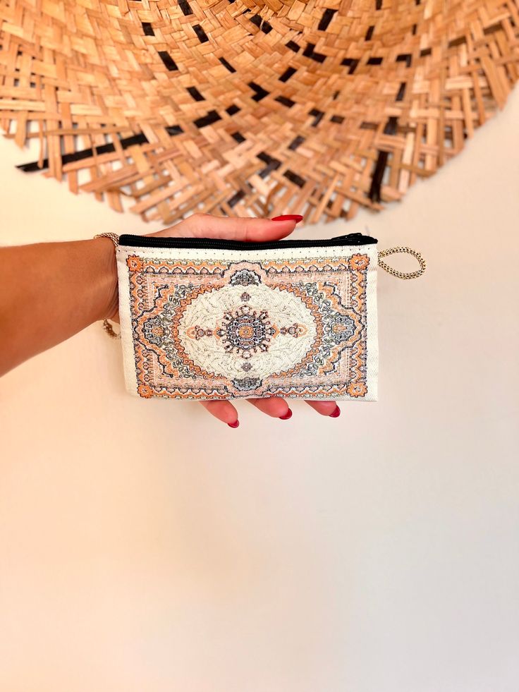 a woman's hand is holding a small purse with an intricate design on it