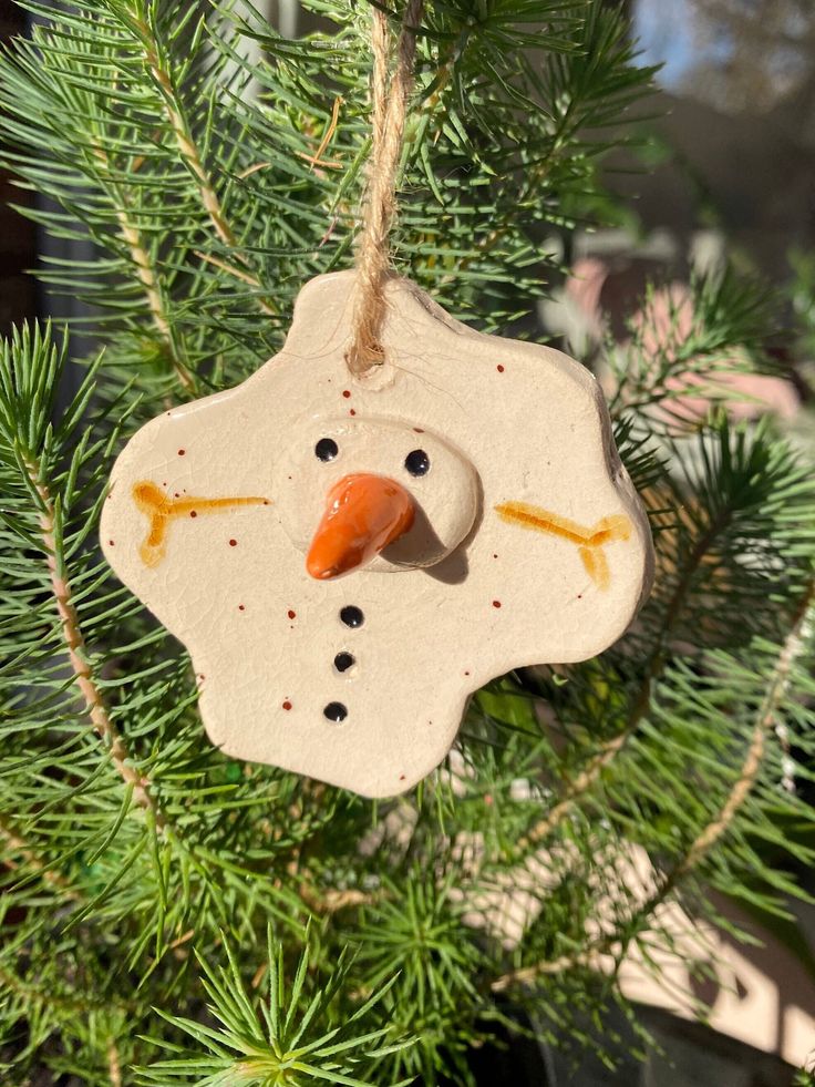 a snowman ornament hanging from a christmas tree in the shape of a face