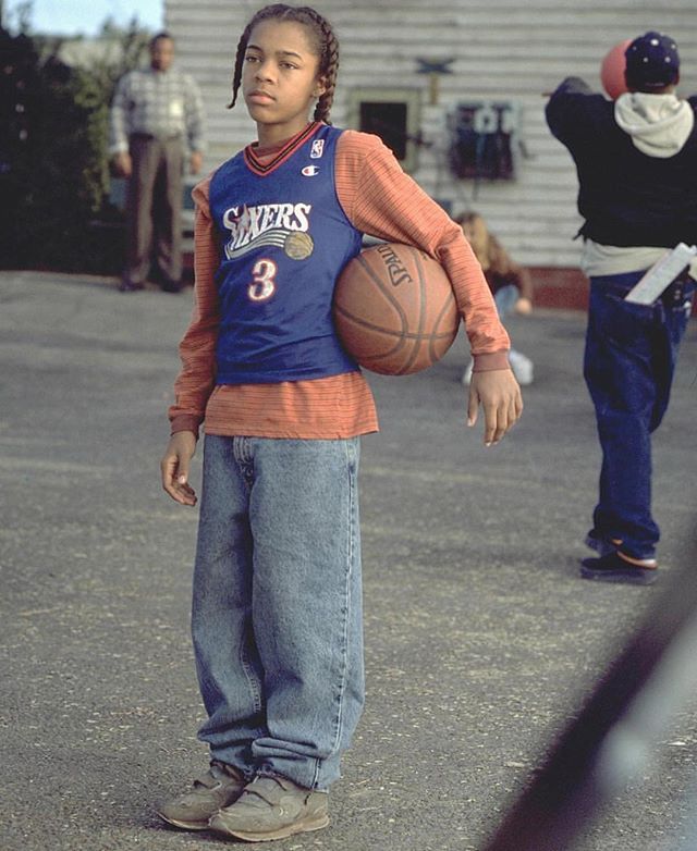 a young boy holding a basketball while standing in front of another person with other people