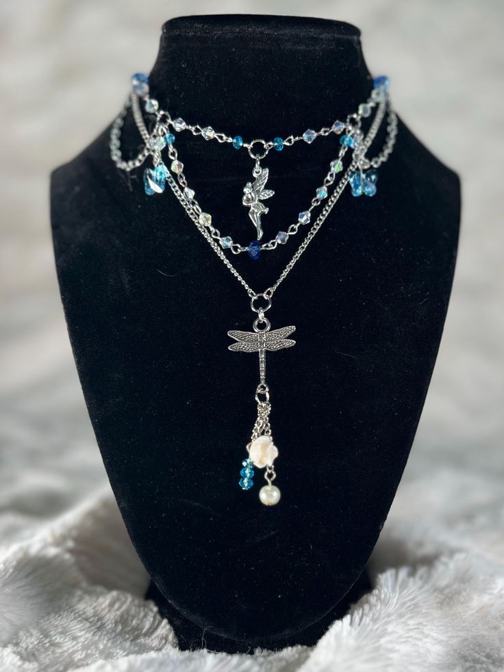 Embrace your inner magic with our silver layered necklace, featuring blue and clear beads and whimsical fairy and dragonfly charms. Perfect for adding a touch of fantasy to any outfit. Silver Layered Necklace, Whimsical Fairy, Layered Necklaces Silver, Dragonfly Charm, Clear Beads, Layered Necklace, Layered Necklaces, Pendant Necklaces, Favorite Jewelry