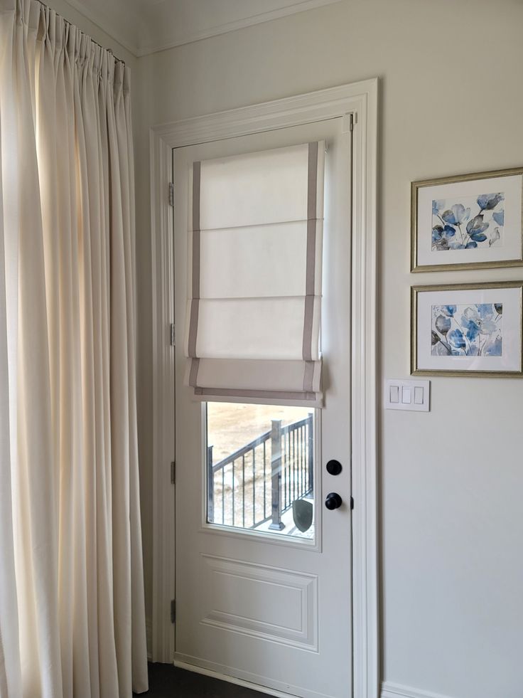 an open door with white curtains and pictures on the wall