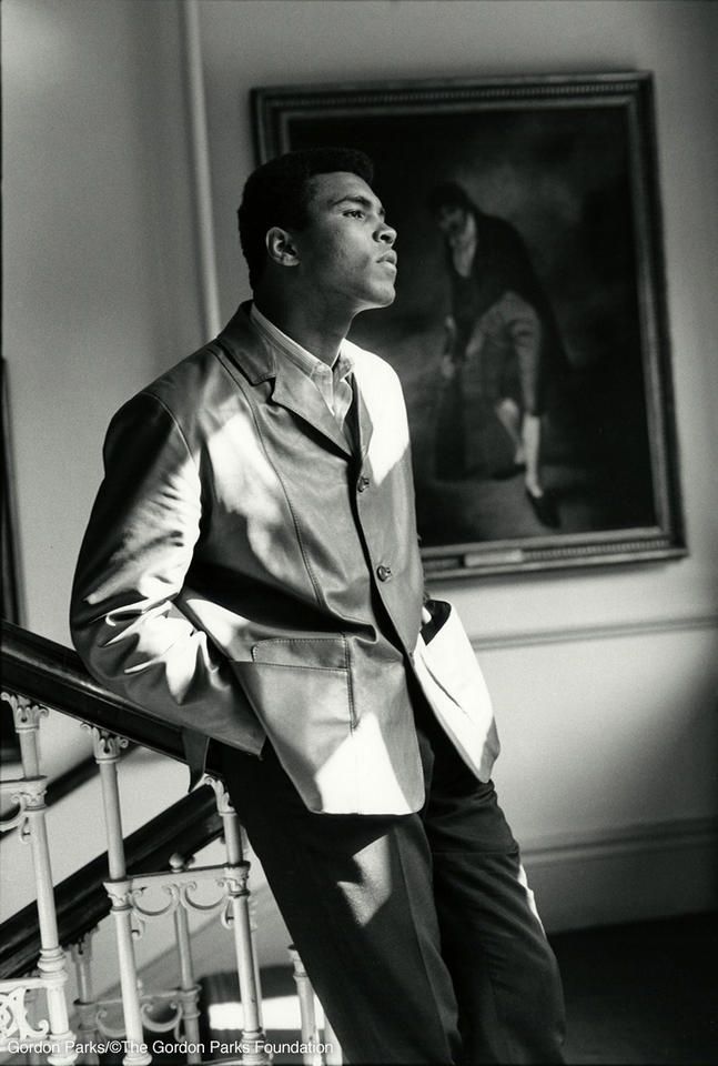 a black and white photo of a man in a suit standing at the top of stairs