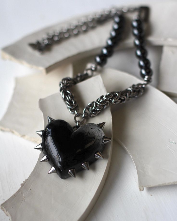 The necklace is made of steel and metal fittings with blackening.  The necklace is short, with a heart pendant relevant for 2024. the spikes are made of steel, the heart is epoxy resin. the author's technique is completely handmade. a glossy-coated heart. The necklace is 19,5 inches long. You can fix the lock in a shorter version. Lock:  1/2 inch carabiner Do not expose to prolonged contact with water, leave in the sun. avoid contact with creams and perfumes. observing these rules, the decoration will delight you for a long time Grunge Heart-shaped Metal Necklace, Punk Black Necklace With Heart Pendant, Black Punk Heart Pendant Jewelry, Black Punk Heart Pendant Necklace, Punk Black Heart Pendant Necklace, Punk Style Black Heart Pendant Necklace, Punk Style Heart Necklace For Gift, Punk Style Metal Necklace With Heart Pendant, Punk Style Metal Heart Pendant Necklace