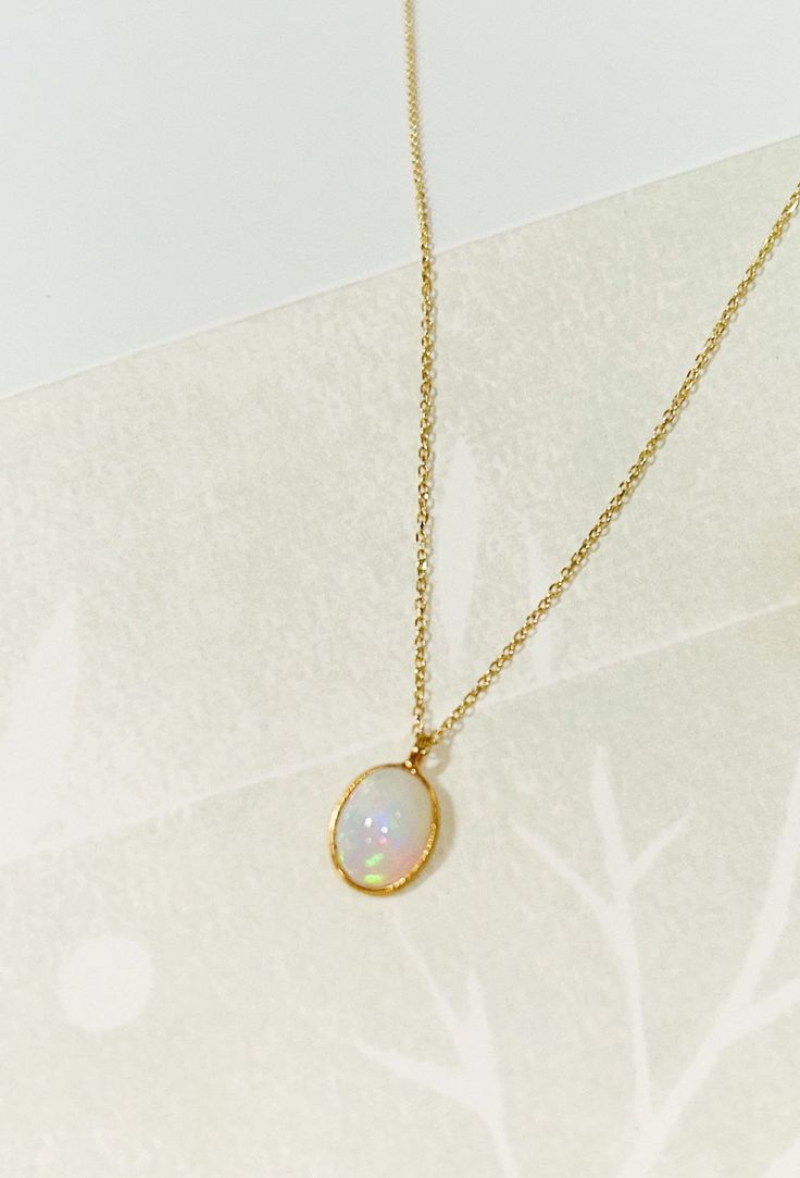 "Oval Opal necklace Oval Opal bezel set pendant on a double rope dainty chain. Charm pendant is made in 18k gold set on a dainty 14k Yellow Gold double rope chain. Necklace length is 16\" and sits under your clavicle. A perfect necklace that is beautiful all year round. + Ethiopian Opal Charm * 9x11mm  + 18k Gold bezel finish + 14k Yellow Gold Double Rope chain. + Approx. 16\" chain + Comes packaged in our signature box + Please note all Mantle 14k gold pieces are made-to-order. In stock items s Gold Dainty Necklace Black Opal, Oval Opal Jewelry With Bezel Setting, Oval Cable Chain Jewelry Gift, Oval Cable Chain Jewelry As Gift, Gift Jewelry With Oval Cable Chain, Gold Plated Necklaces With Bezel Setting For Gifts, Gold Plated Bezel Setting Necklace Gift, Oval Cable Chain Necklace As A Gift, Oval Pendant Gemstone Necklace For Gift