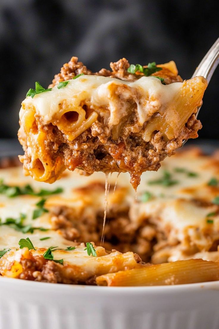 a spoon full of lasagna casserole being lifted from a white dish