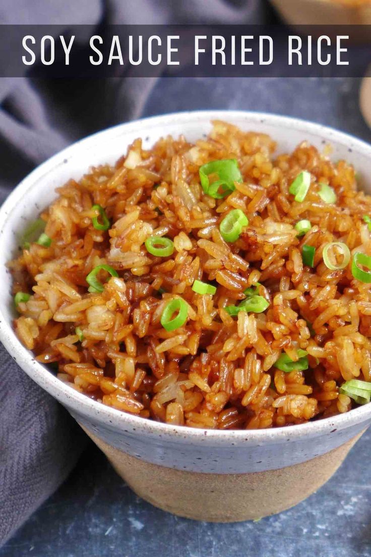 a white bowl filled with fried rice and green onions on top of a blue table cloth