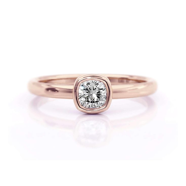 a yellow gold engagement ring with a round brilliant diamond in the center, on a white background