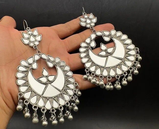 This Exotic Oxidised mirror Earring For Women is made of Alloy. Women love jewellery; specially traditional jewellery adore a women. They wear it on different occasion. They have special importance on ring ceremony, wedding and festive time. They can also wear it on regular basics. Make your moment memorable with this range. This jewel set features a unique one of a kind traditional embellish with antic finish. Item Description: The look is stunning and preciously suitable for all kinds of dress White Chandbali Jewelry With Mirror Work, Silver Metal Chandbalis As Gift, Silver Bohemian Metal Chandbalis, Bohemian Silver Metal Chandbalis, Traditional White Jewelry With Mirror Work, Handmade Silver Chandbalis, Bohemian Danglers For Navratri Gift, Heavy White Chandbalis For Gift, White Temple Jewelry Style Danglers As Gift