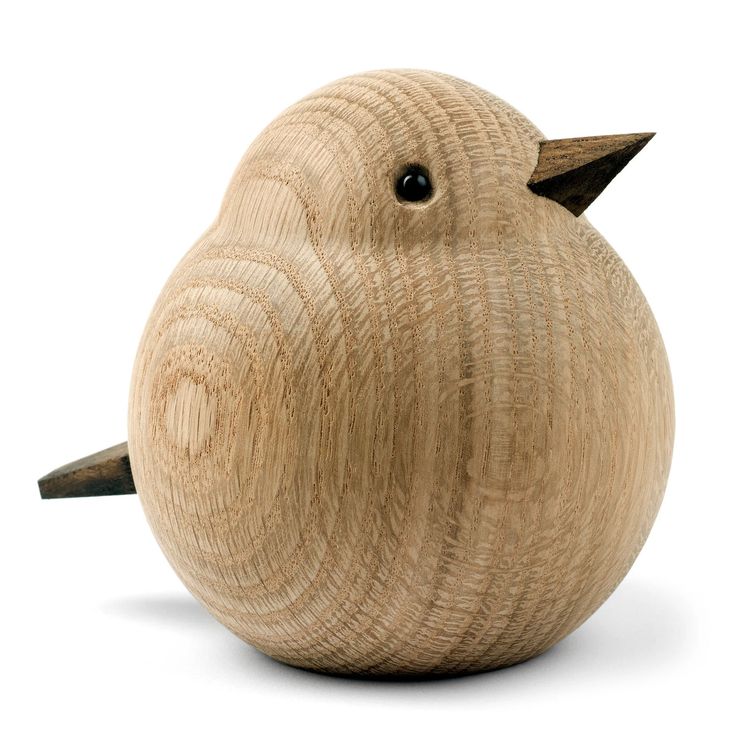 a small wooden bird sitting on top of a white surface