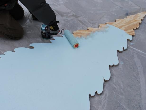 a man is painting a piece of wood with white paint on the floor next to it