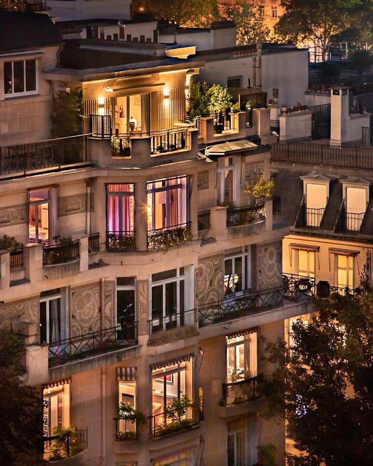 an apartment building with many windows and balconies lit up at night in the city