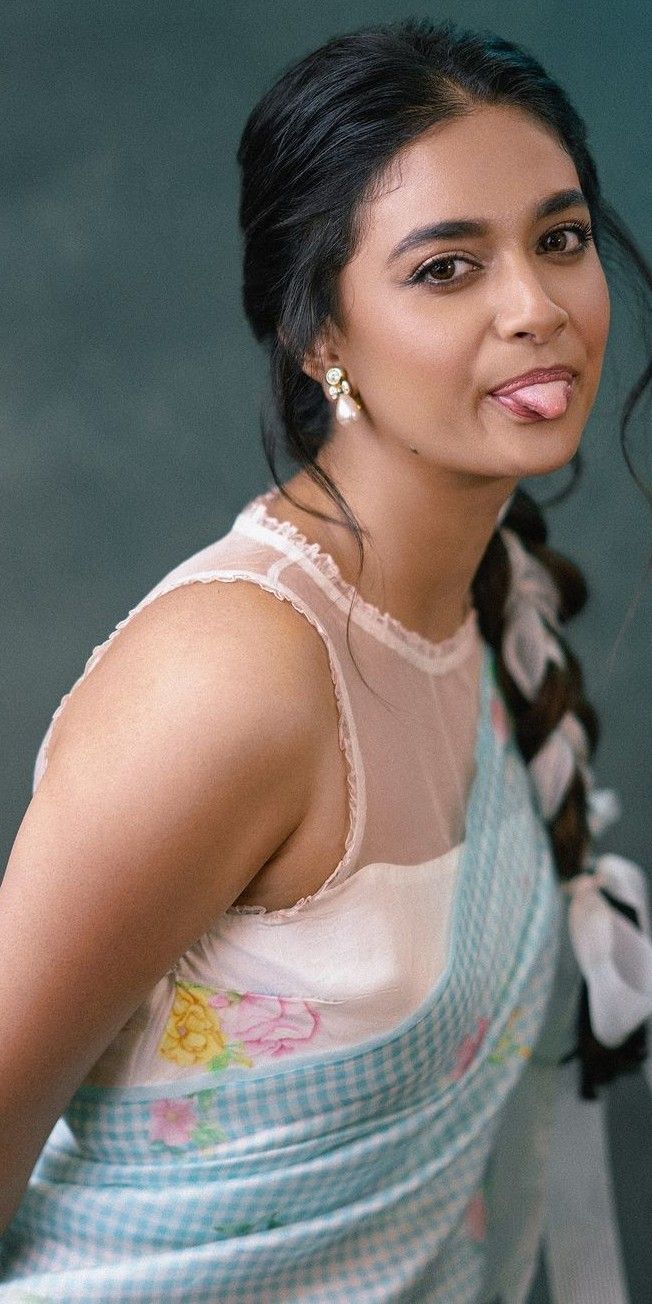 a woman with her tongue out posing for the camera while wearing a blue and white dress