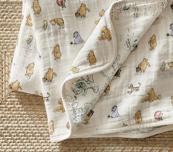 winnie the pooh baby blanket laying on top of a woven placemat with an animal print