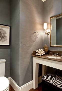 a white toilet sitting under a bathroom mirror next to a sink and a zebra print rug