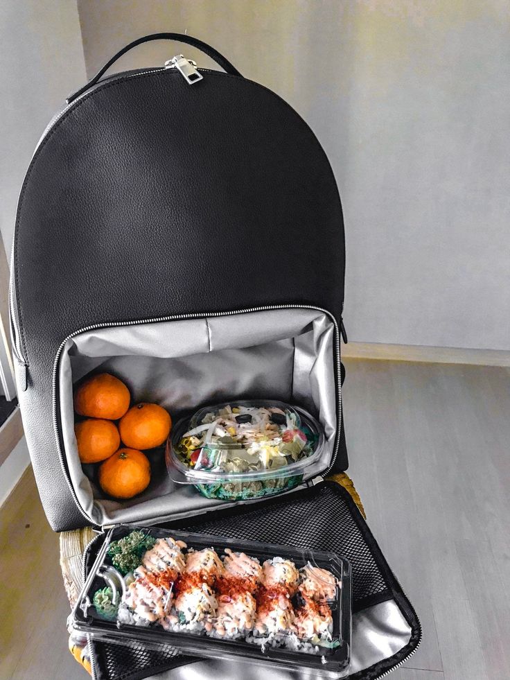 an open backpack with food in it and oranges on the table next to it