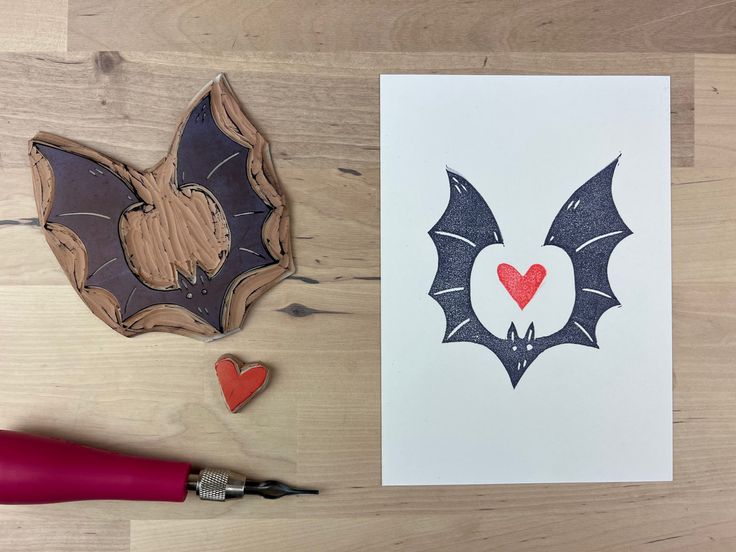 a card with a bat and heart on it next to some crafting supplies like scissors