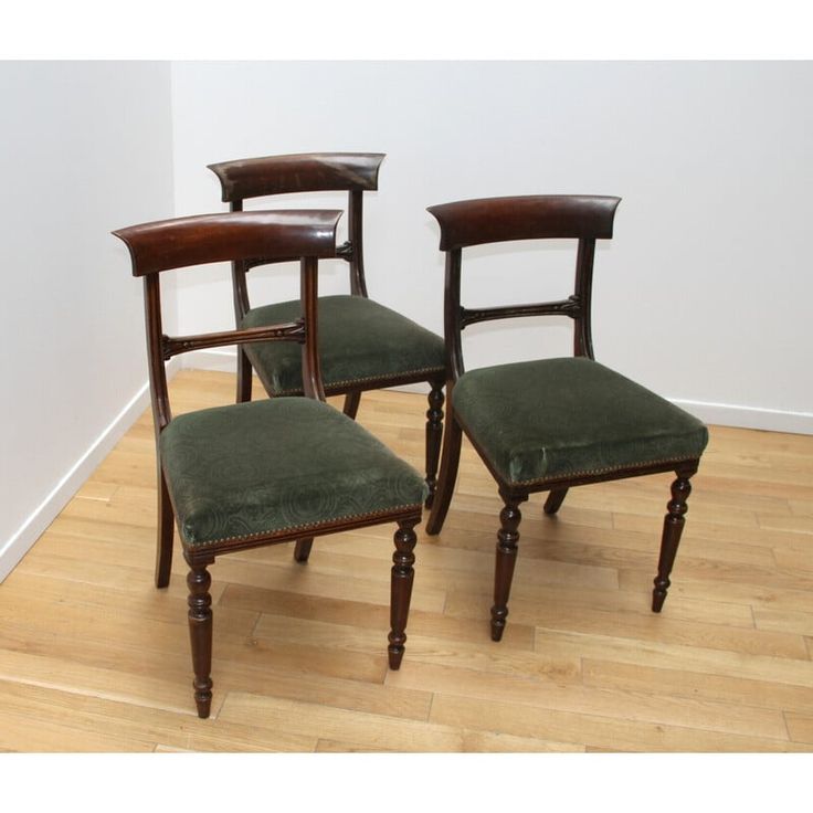 three wooden chairs sitting on top of a hard wood floor