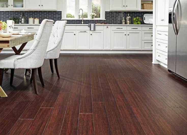 a kitchen with wood flooring and white cabinets is shown in this image, there are four chairs around the table