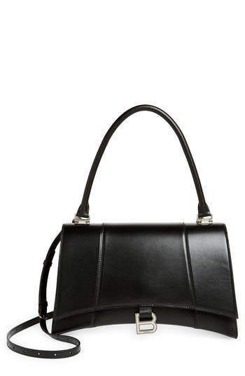 The curvilinear silhouette of this smooth leather satchel recalls the exaggerated shapes and proportions often used by master couturier Cristóbal Balenciaga. B-shaped hardware reveres the brand's legacy while keeping with the current logomania craze. Magnetic-snap flap closure Top carry handle; removable, adjustable crossbody strap Exterior slip pocket Interior zip and wall pockets Structured silhouette with flat base for stability Napa-lambskin lining Leather Made in Italy Designer Handbags Luxury Black Calf Leather Flap Bag, Formal Leather Bag With Double Flap, Luxury Black Double Flap Satchel, Formal Leather Double Flap Bag, Leather Evening Bags With Double Flap, Leather Evening Bag With Double Flap, Leather Double Flap Evening Bag, Timeless Evening Bag With Double Flap, Black Calf Leather Flap Bag For Evening