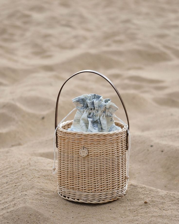 a wicker basket with cloths in the sand