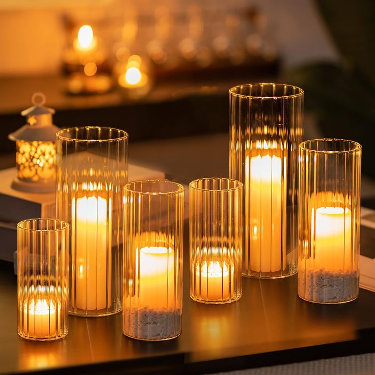 candles are lit in glass vases on a table next to a tea light candle holder