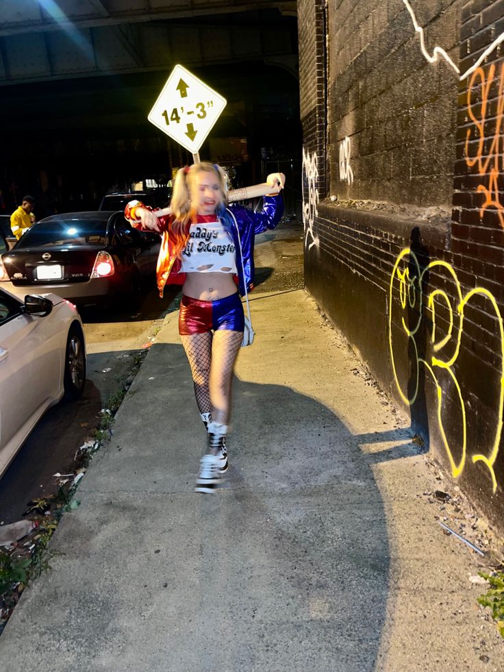 a woman walking down a sidewalk with graffiti on the wall