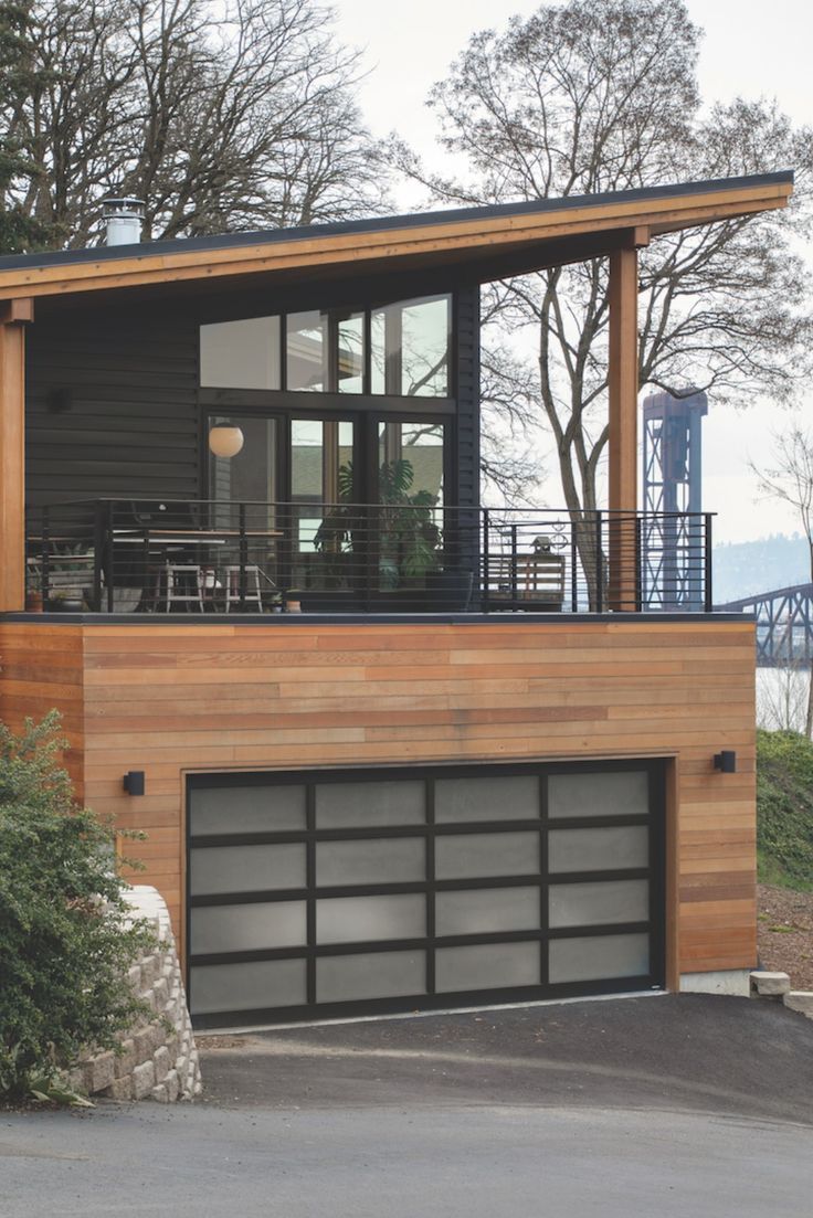 a modern house with wood siding and glass windows on the top floor, along with an attached deck