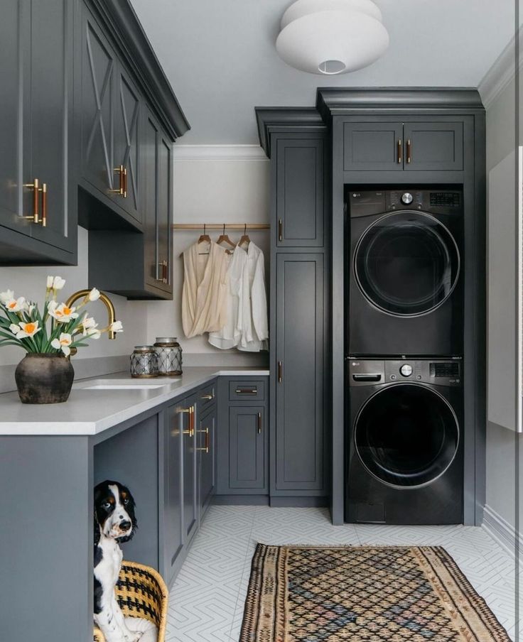 a washer and dryer are in the middle of a room with gray cabinets