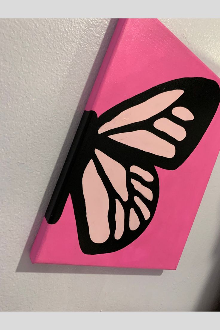 a pink and black butterfly painted on a canvas mounted to the side of a wall