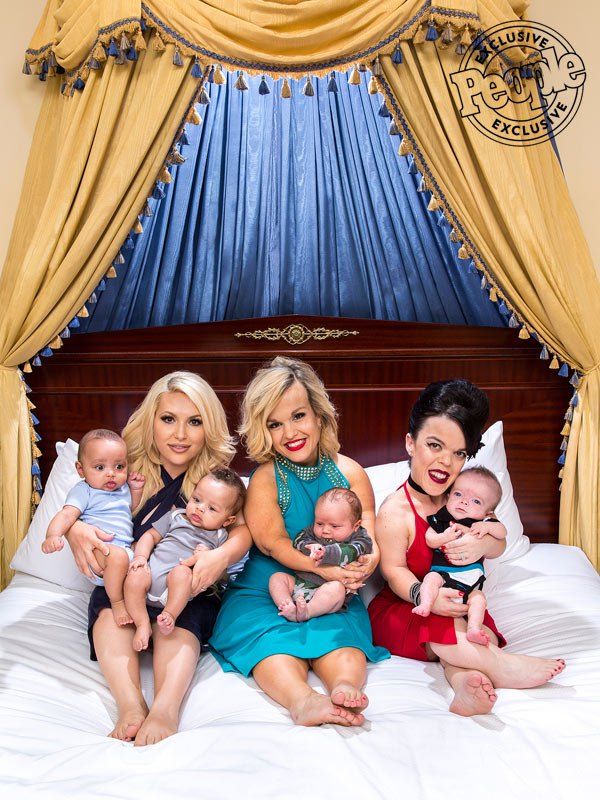 a group of women sitting on top of a bed holding babies