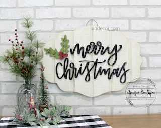 a wooden sign that says merry christmas on the side of a table with greenery