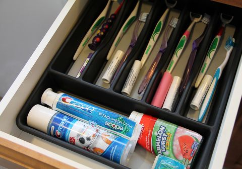 an organized drawer with toothbrushes, toothpaste and other items