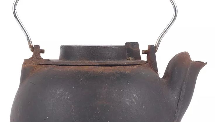 an old iron teapot with a handle on the side and no lid is shown