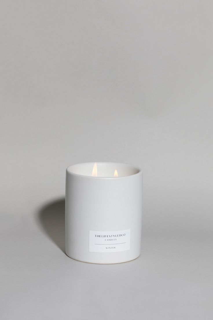 a white candle sitting in front of a gray background with the words,'candleshop'written on it