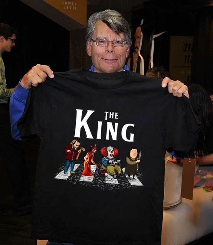 a man holding up a black t - shirt with the words the king on it