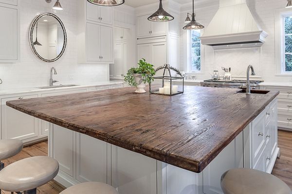 a large wooden counter top in a kitchen next to stools and an island with lights