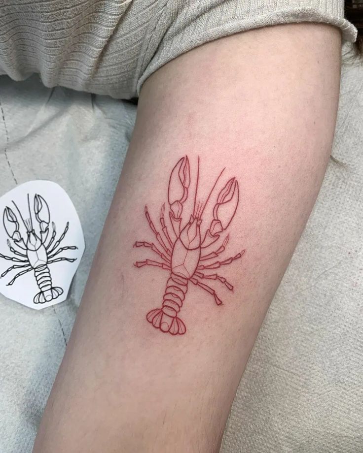 a red ink lobster tattoo on the arm