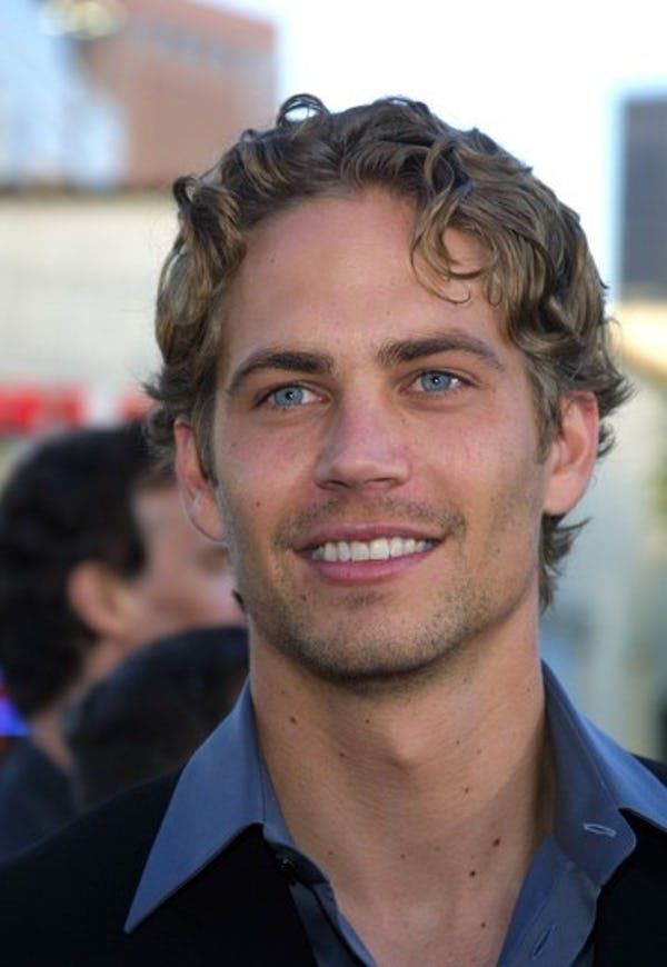 a close up of a person wearing a black shirt and smiling at the camera with other people in the background