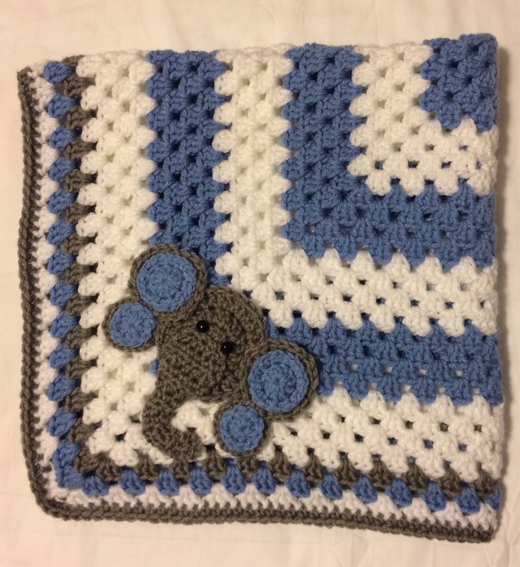 a blue and white crocheted blanket with a teddy bear on it