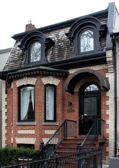 a brick house with black iron railings and windows