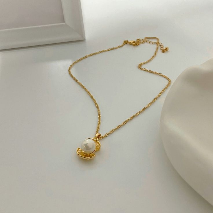 The Pearl Pendant Necklace, set in 18k gold plating, elegantly combines the timeless beauty of a pearl with contemporary design. It’s a sophisticated piece, ideal for adding classic charm to any attire. Luxury Gold-tone Pearl Chain Necklace, Luxury Gold-tone Jewelry With Pearl Pendant, Gold-tone Pearl Necklace With Pearl Chain, Gold-tone Pearl Chain Necklace, Elegant Pearl Chain Jewelry, Luxury Gold-tone Jewelry With Pearl Chain, Luxury Gold-tone Pearl Jewelry, Elegant Pearl Chain Necklace With Pearl Pendant, Gold Plated Jewelry With Pearl Charm