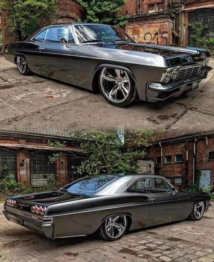 an old black car with chrome rims parked in front of a brick building on the street